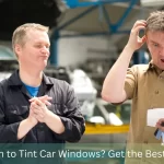 A confused customer holding a receipt while a mechanic stands nearby, both in an auto shop environment. The scene highlights the cost consideration for services like window tinting. Text overlay reads 'How Much to Tint Car Windows? Get the Best Price Now!