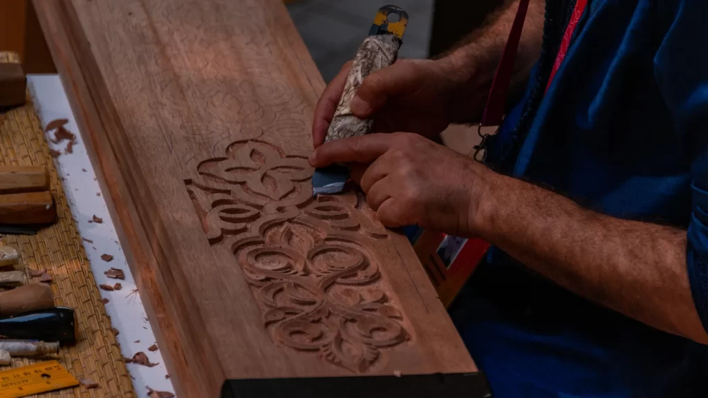 Traditional vs CNC Wood Carving – An artisan hand-carving intricate wooden designs with chisels.