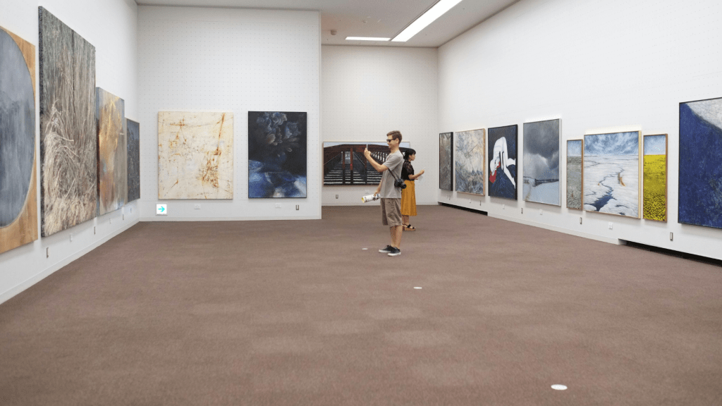 Visitors exploring a contemporary art gallery with digital elements, showcasing the evolution of E-Galleries in Art.