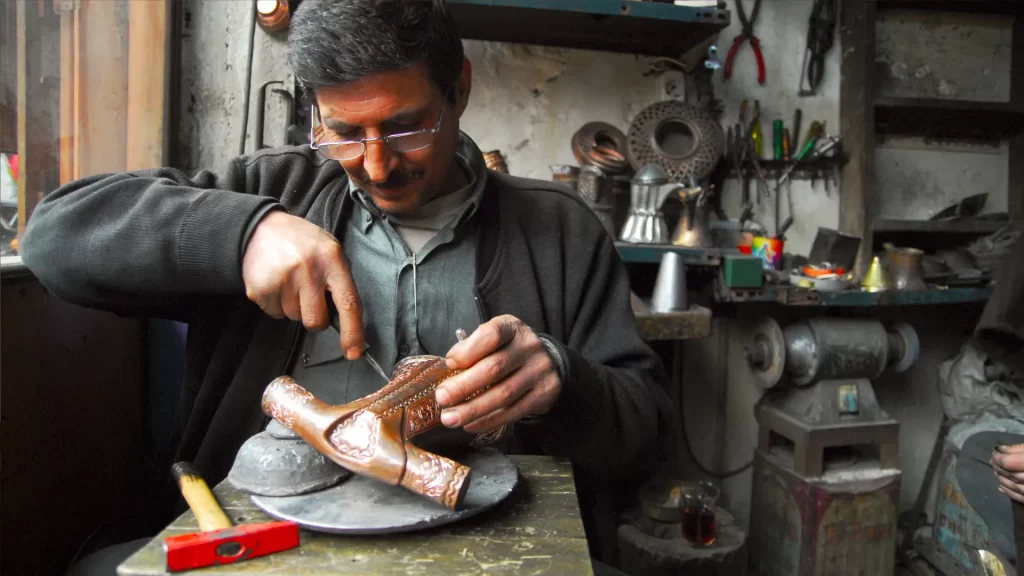 A skilled artisan engraving delicate patterns on a wooden surface, demonstrating the craftsmanship behind silhouette art in wood designs.