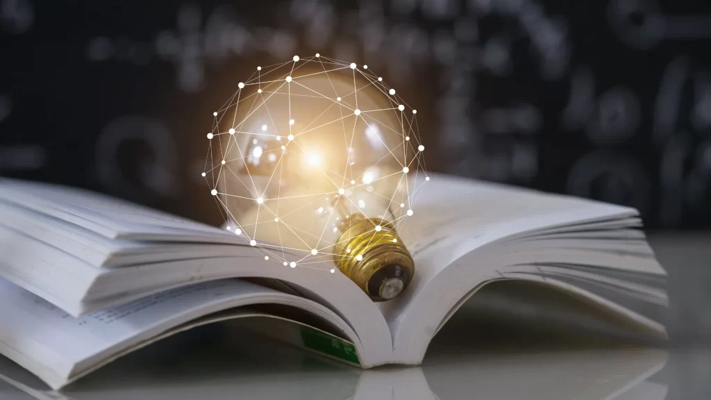 A glowing light bulb placed on a book, signifying the connection between knowledge and MN educator license lookup.