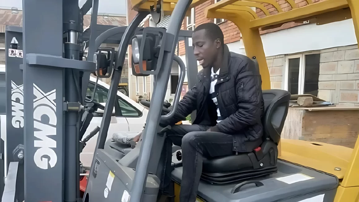 Steven Maranga Nyambega operating a forklift outdoors in a work environment, wearing a black jacket and focused on the machine controls.