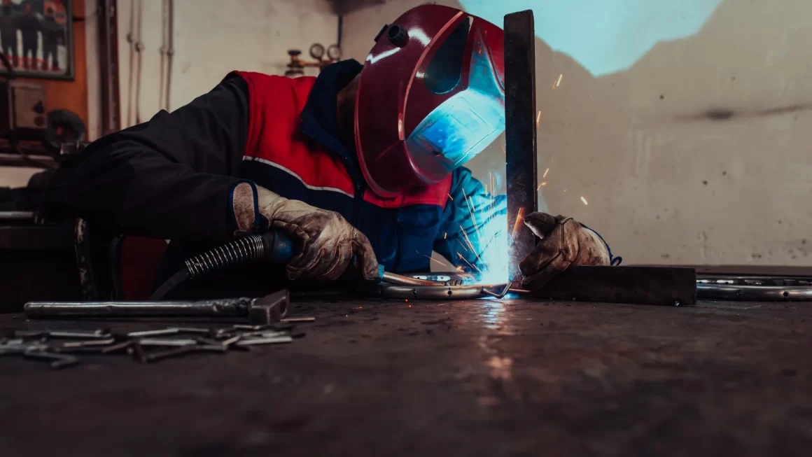 A welder in protective gear producing sparks during welding, emphasizing craftsmanship and manufacturing processes linked to where Powermatic tools are manufactured.