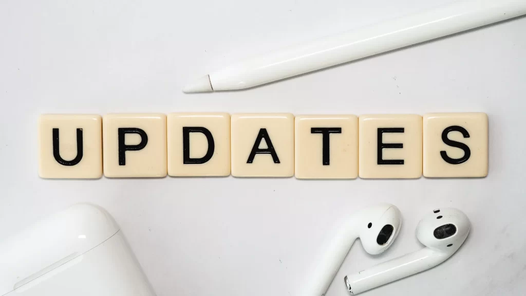 Scrabble tiles spelling 'UPDATES' with AirPods, symbolizing the latest updates from ScoopUpdates.com.